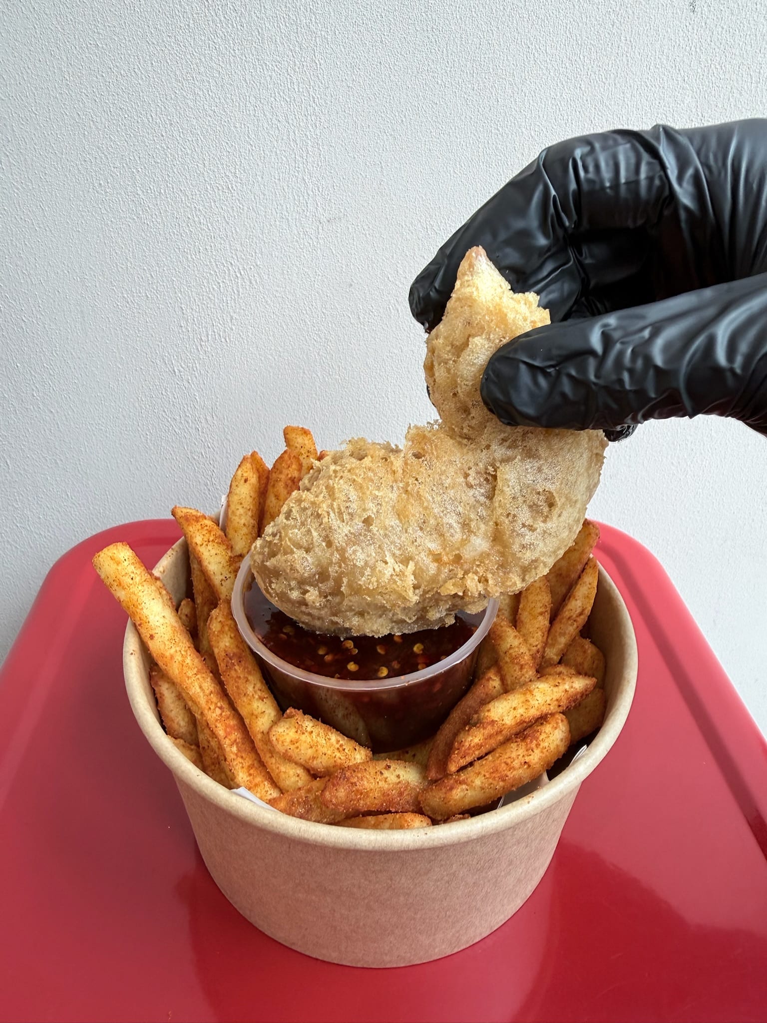 A hand reaching in for a piece of INYUN fried chicken over a shared tray of chips and dips