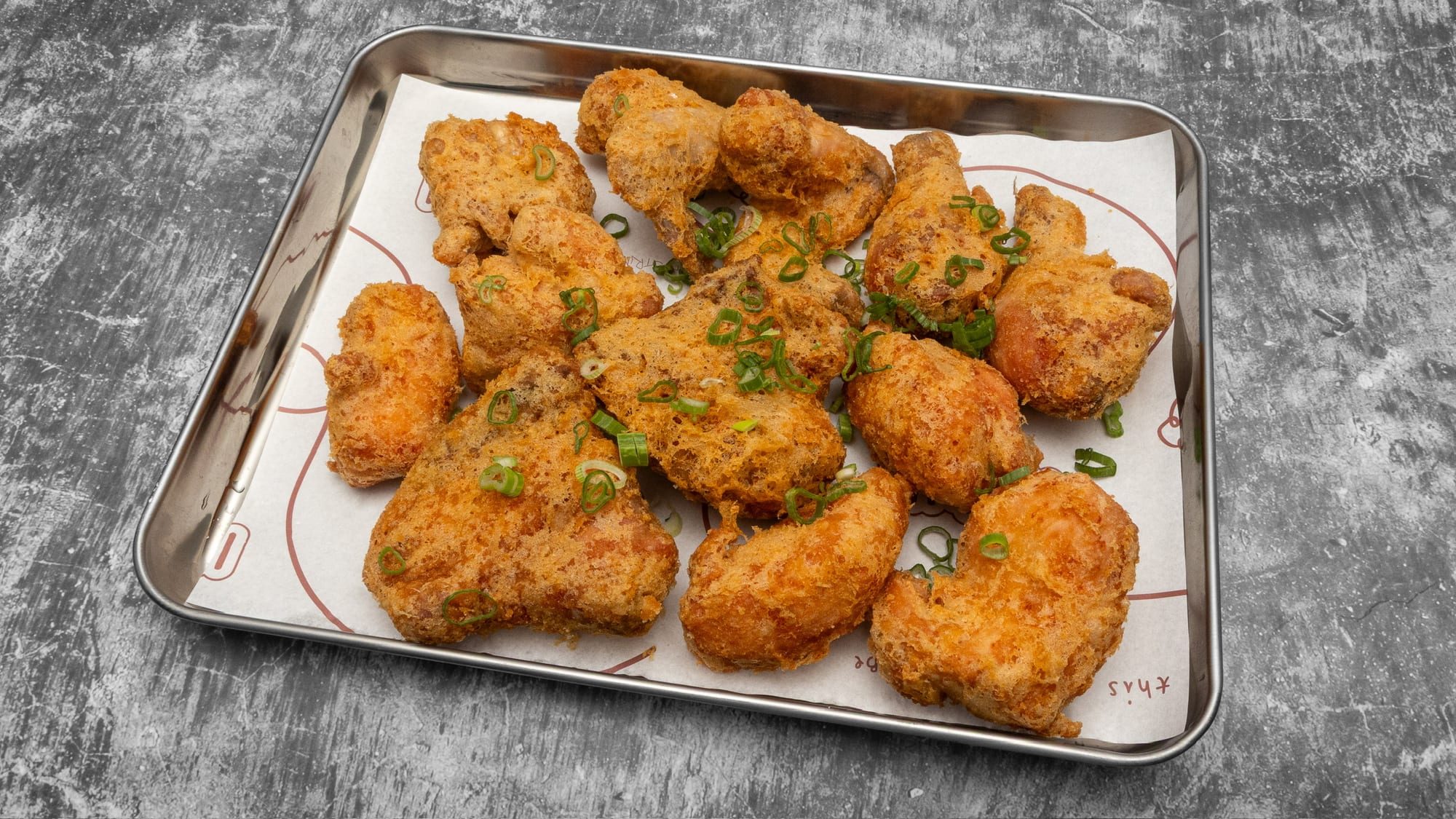A whole INYUN fried chicken, twelve to thirteen golden pieces on a branded tray